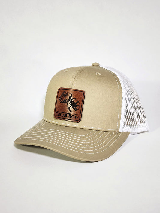 cedar row brand leather patch with cotton artwork on a khaki trucker hat
